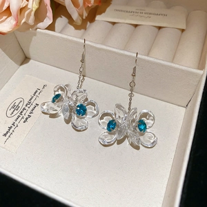 Detail view of acrylic flower earrings with blue rhinestones in a soft jewelry box