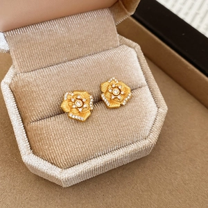 Macro shot of gold-plated flower stud earrings with zircon inlay in a velvet jewelry box