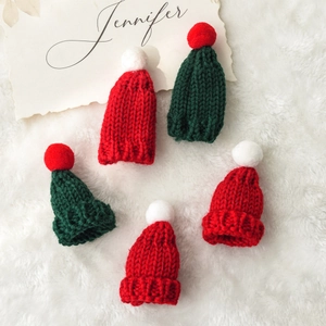 Detailed view of mini knitted Christmas hats in red and green with soft yarn texture