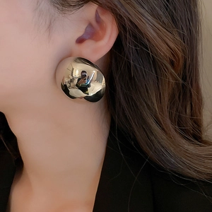 Close-up of chunky silver striped metal teardrop earrings on a model showing metallic luster