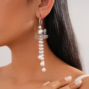 Macro view of silver butterfly tassel earrings with cubic zirconia and pearls on model