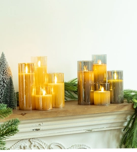 Macro shot of LED pillar candles in gold and smoky grey glass on a festive wooden mantel
