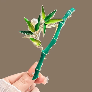 Detail of bamboo shaped metal hair claw with green enamel finish and pearl accent