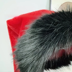 Close-up of red velvet Christmas hat featuring fluffy black faux fur trim and white pompom