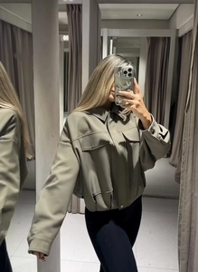 Dettaglio della giacca in finta pelle grigio-verde con tasche grandi e colletto a camicia