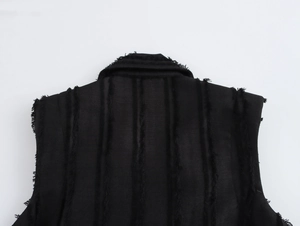 Détail d'une robe sans manches en tweed noir avec tissu texturé et finition effilochée