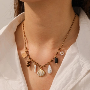 Close-up of ocean-themed necklace with shell, pearl, and gold-rimmed charms on cord