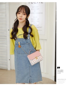Close-up of pink flap and plaid pattern on small square crossbody bag with gold chain