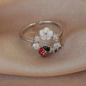 Macro detail of silver flower ring with ladybug enamel and cubic zirconia stones