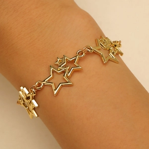 Détail d'un bracelet doré avec étoiles évidées porté au poignet pour un style chic