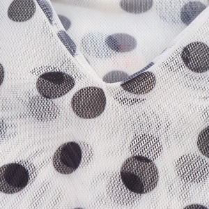Detailed macro view of black polka dot print on breathable white mesh fabric V-neckline