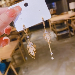 Detail of asymmetric gold leaf drop earrings with sparkling pavé cubic zirconia