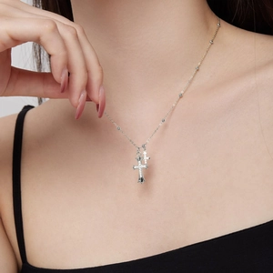 Close-up of double layered silver cross necklace with pavé zircon stones on female model