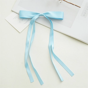 Detail of light blue satin bow hair clip with long ribbons on white aesthetic background