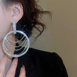 Gros plan d'un mannequin portant des boucles d'oreilles à pompons argentés strassés