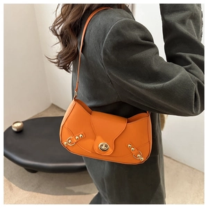 Detail of bright orange leather shoulder bag with gold metal twist lock and studs