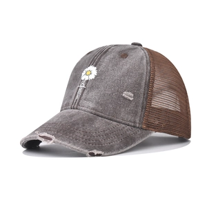 Detail of washed denim baseball cap with daisy blessed embroidery and distressed holes