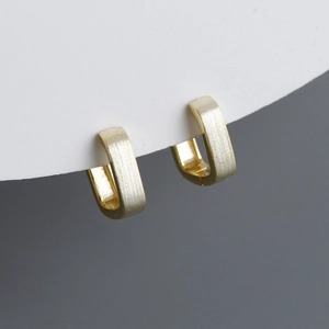 Macro shot of gold square leverback earrings with brushed matte metallic texture