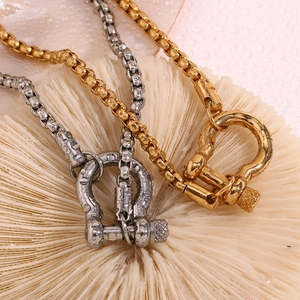 Detail of gold and silver box chains with horseshoe clasps on white coral background