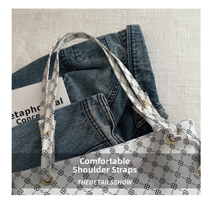 Detail view of white tote bag featuring black vintage print and gold metal rivet hardware