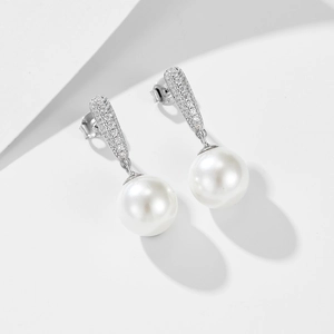 Close-up of elegant silver pearl earrings with micro-set zircon stones on white background