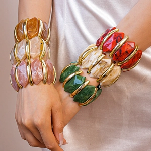 Détail de bracelets en résine colorée avec bords en métal doré sur tissu en soie