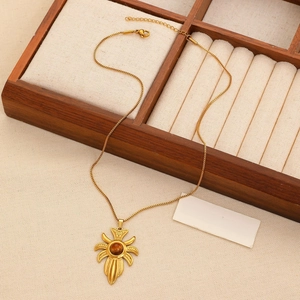 Close-up of golden sunflower pendant with tiger eye stone on a wooden jewelry tray