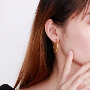 Classic gold stainless steel hoop earring shown on a model with a clean white background