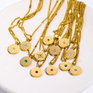 Detailed close-up of 18K gold-plated stainless steel birthstone necklaces on stone base