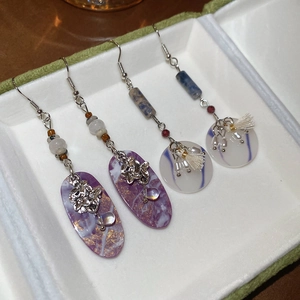 Detail view of bohemian resin earrings with purple marble texture and white silk tassels