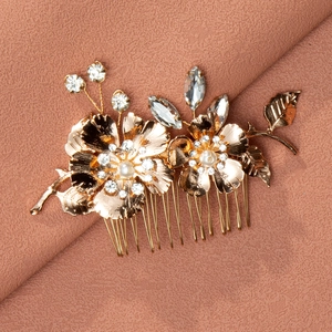 Detail view of golden flower bridal hair comb with pearls and rhinestones on fabric