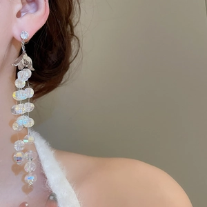 Dettaglio di orecchini a nappa con petali e cristalli iridescenti indossati da una modella