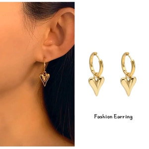 Detail of gold heart hoop earrings showing the 3D pendant and on-model wear style