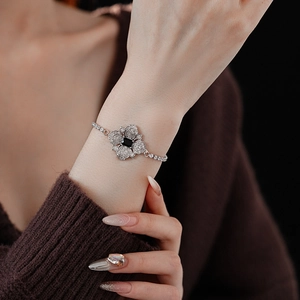 Close-up of a silver flower bracelet with a black square gemstone on a model's wrist