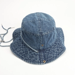 Detailed macro view of washed blue denim bucket hat with metal button and chin strap