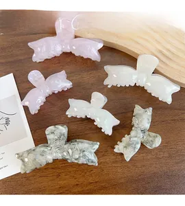 Lot de six pinces à cheveux noeud en acétate rose, crème et marbre sur fond en bois