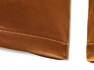 Detailed view of bronze satin wide-leg pants showing premium stitching and fabric texture