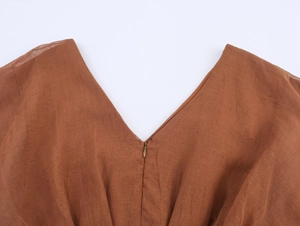 Detailed view of the V-neckline and fine fabric texture on the brown shift dress