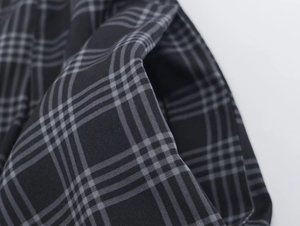 Detailed macro view of black and grey plaid fabric texture with precise stitching