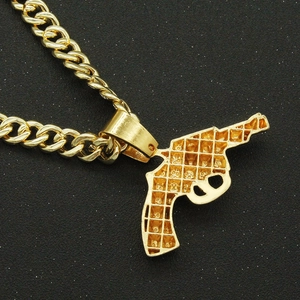 Macro shot of hip hop style gold gun pendant with detailed grid texture on black surface