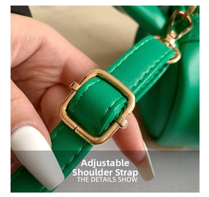 Detail of adjustable green crossbody bag strap with gold metal buckle and stitching