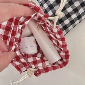 Detail of red and black checkered drawstring pouches organizing cosmetics and skincare items