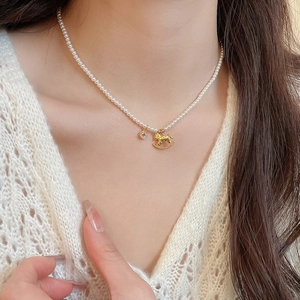 Close-up of a pearl necklace featuring a golden horse pendant with zircon accents on a model