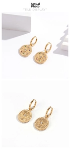 Detailed macro view of bohemian gold earrings with sunburst texture and colored zircons