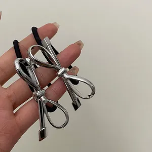 Silver bow metal hair ties with black elastic bands shown in hand for detail