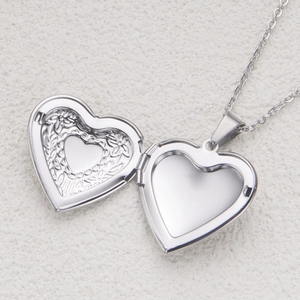 Macro view of open silver heart locket necklace with internal floral engraving