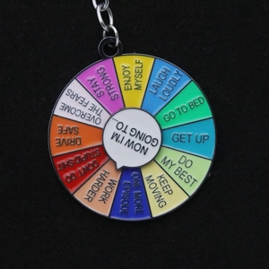 Close-up of a colorful rainbow rotating enamel keychain with social battery mood phrases