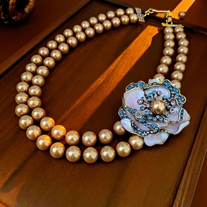 Macro detail of vintage double-layer champagne pearl necklace with floral enamel pendant