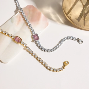 Close-up of gold and silver tennis bracelets with pink rectangular crystals on marble