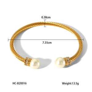 Detail view of gold twisted cable bangle with white pearls and crystal accents on white background
